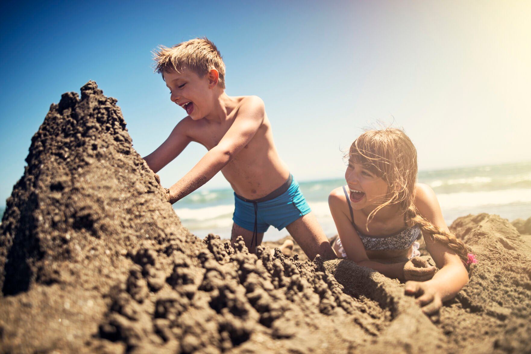 Brother and sister building a sandcastle on beach